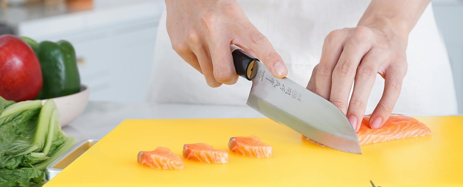 Vibrant kitchen scene with chef slicing fresh salmon fillets on yellow cutting board.